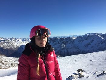 Young woman standing on snow covered field during sunny day