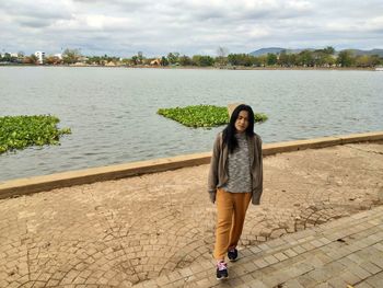 Full length portrait of smiling woman standing on shore