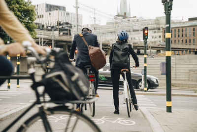 Rear view of businessman and businesswoman with bicycles on street in city