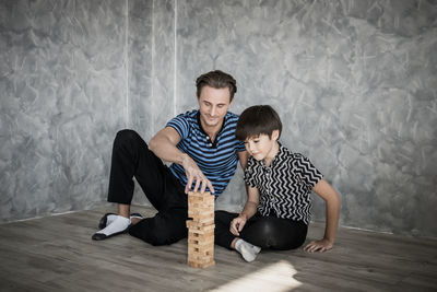 Father and son playing with wooden blocks on hardwood floor at home