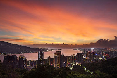 Illuminated cityscape against sky during sunset