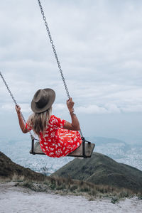 Rear view of woman on swing against sky