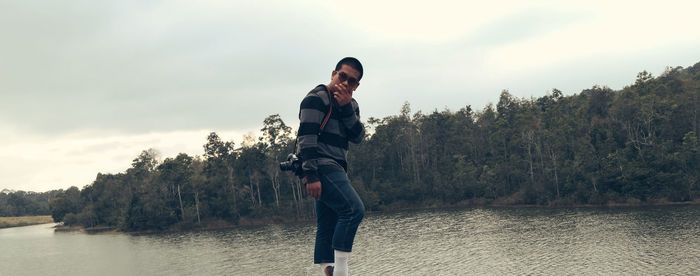 Portrait of man standing by lake against sky