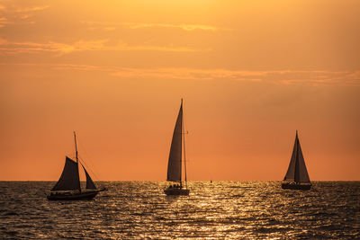 Sailboat sailing on sea against sky during sunset