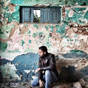 Man kneeling against weathered wall