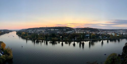 Scenic view of river by buildings against sky during sunset