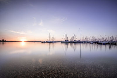 Sailboats in sea against sky during sunset