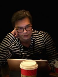 Close-up of young man sitting against black background