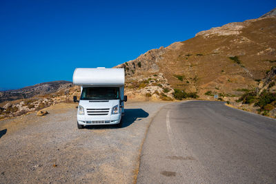 Road by mountain against clear blue sky