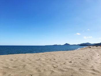 Scenic view of beach against clear blue sky