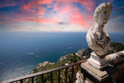 Statue by sea against sky