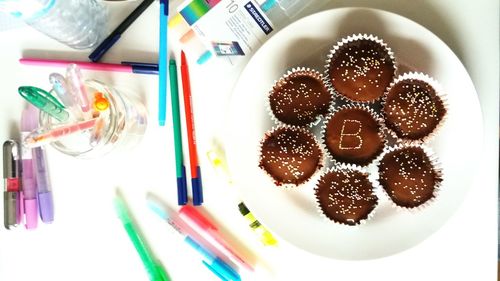 Directly above shot of felt tip pens and cupcakes on table
