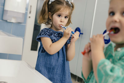 Little girls brushing their teeth in bathroom of a kindergarten