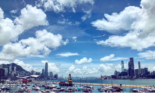 Sailboats in sea by modern buildings against sky
