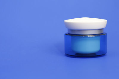 Close-up of glass of jar against blue background