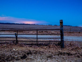 Wooden fence on field against blue sky