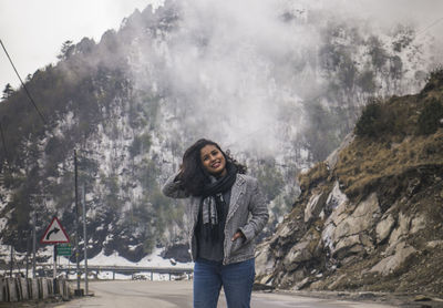 Portrait of young woman standing on snow covered mountain