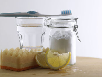 Close-up of baking soda in glass jar vinegar and lemon on table