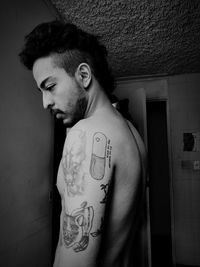 Portrait of young man standing against wall at home