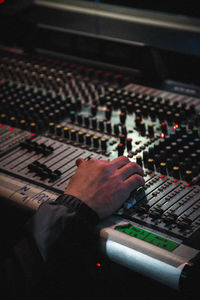 Cropped hand of man using sound mixer in recording studio