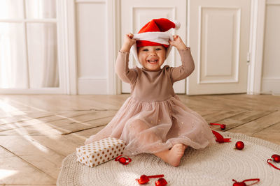 A cheerful emotional little child girl in red santa claus hats is having fun on christmas holiday