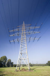 Electricity pylon on field against clear blue sky