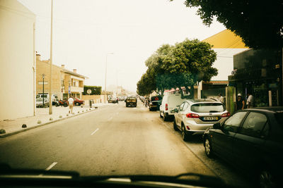 Cars on street in city against sky