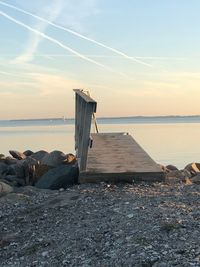 Lifeguard hut on beach against sky during sunset