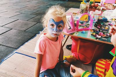 Portrait of cute girl with make-up sitting on floor