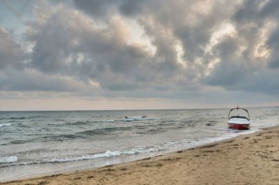 Scenic view of sea and boat against cloud sky