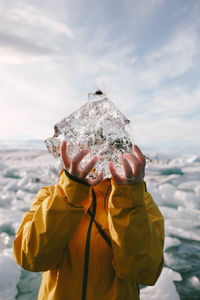 Low angle view of hand holding ice against sea