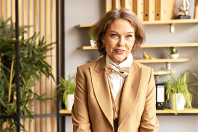 Portrait of a business smiling woman in a suit in the office at work. woman's hands hold glasses 