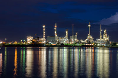 Illuminated factory against sky at night