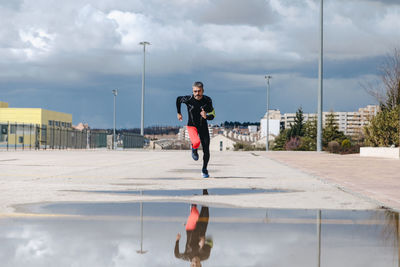 Mature man jogging on road against cloudy sky