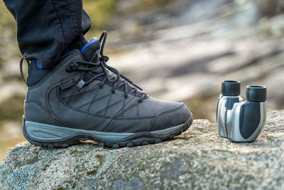 Low section of man by binoculars on rock