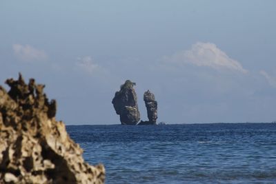 Rock formation in sea against sky