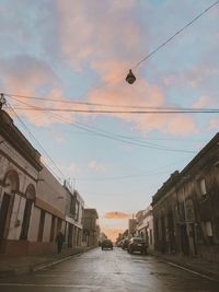 Street amidst buildings against sky at sunset