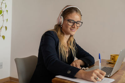 Woman working at home with laptop and papers on desk and headphones. home office . gray notebook 