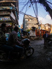 People sitting on street against buildings in city