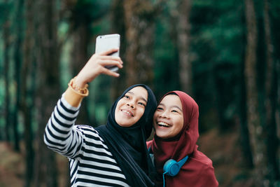 Teenage girl with friend taking selfie from mobile phone