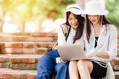 Midsection of woman using mobile phone while sitting outdoors