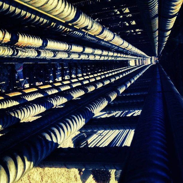 indoors, pattern, low angle view, architecture, in a row, built structure, diminishing perspective, repetition, modern, ceiling, design, metal, the way forward, railing, metallic, no people, day, architectural feature, sunlight, transportation