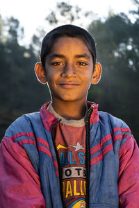 Portrait of teenage boy standing against trees
