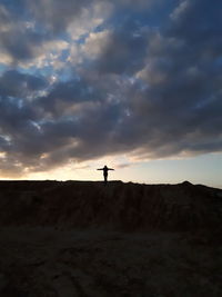 Silhouette woman standing on cliff against sky during sunset