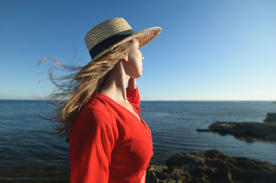 Woman wearing hat on beach against sky