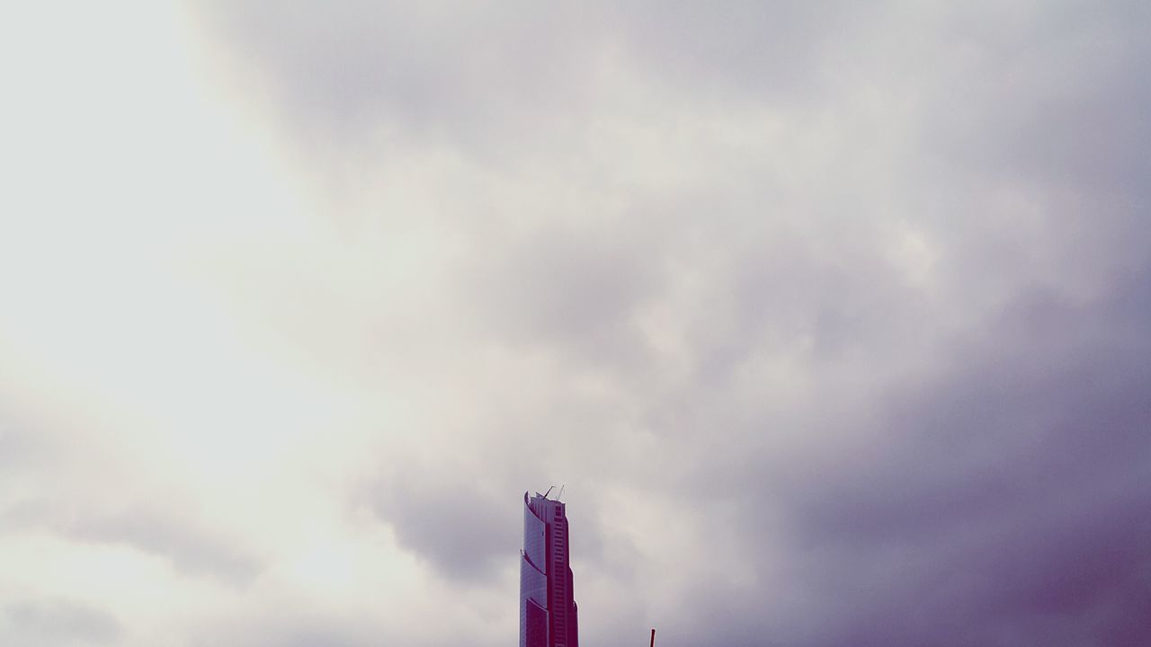 low angle view, sky, cloud - sky, cloudy, cloud, built structure, weather, architecture, overcast, building exterior, outdoors, tall - high, no people, day, high section, nature, cloudscape, street light, pole, tower