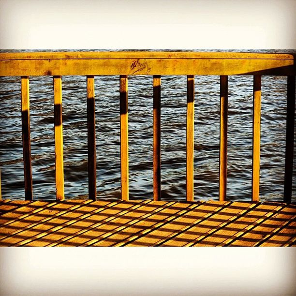 built structure, architecture, pattern, railing, building exterior, yellow, in a row, wood - material, repetition, outdoors, day, no people, sky, sea, pier, water, side by side, metal, protection, wall - building feature