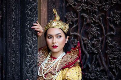 Woman in traditional clothing looking away while standing against wall