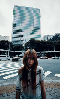 Portrait of beautiful woman in city against sky