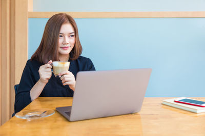Young woman drinking coffee while sitting on table